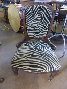 A Victorian mahogany framed nursing chair on turned legs and castors, upholstered in zebra