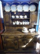 An Oak Dresser, the canopied top with three shelves and two cupboards to either side seated on a