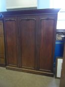 A large Victorian mahogany compactum having three doors enclosing shelves and hanging space, the