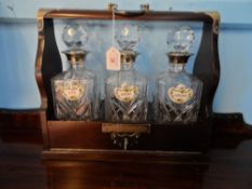 Antique oak Tantalus with three glass decanters.