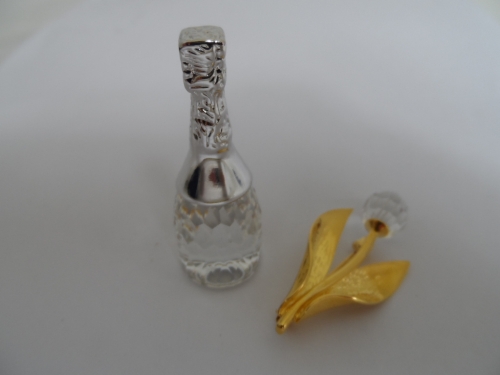 A Swarovski champagne bottle together with a Swarovski brooch and a rough hewn portion of amethyst