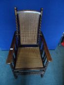 Edwardian oak reclining armchair being cane seated and backed, the arms being supported on decorated