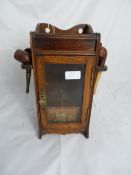 A small oak smoker`s cabinet having a single drawer and pipe rack to each side with five pipes.