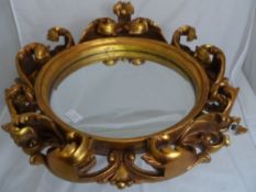 An ornate gilt porcelain round mirror with foliate decoration.