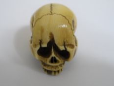 Japanese ivory Netsuke in the form of an intricately carved human skull having defined features,