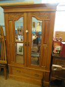 An Edwardian satinwood wardrobe having two mirrored doors and a drawer below on a plinth base with