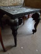 An Indian Style Ebonised Occasional Table, the table having four carved legs in the form of