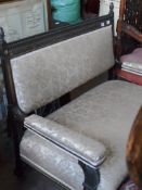 An Edwardian Ebony Sofa; the sofa being a two seater and having a carved piano key rail with gilding