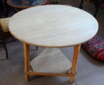 A Round Pine Farmhouse Kitchen Table; the table being on a tripod base with an under shelf,