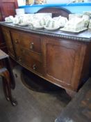 An Edwardian mahogany bow fronted sideboard on ball and claw feet having a cupboard to each side and