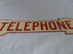 A vintage cream and red Telephone sign, the enamel sign shaped like an arrow.