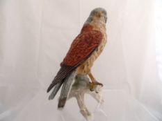 A Goebel Figure of a Hawk, seated on a branch, decorated in matt polychrome, impressed and painted