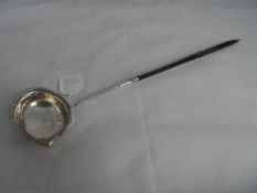 Antique silver brandy ladle, having a turned ebony handle, the ladle being embossed with flowers (