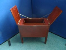 A vintage flip top mahogany sewing box with front drawer and side cupboards