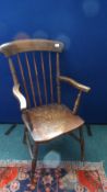 AN ANTIQUE SPINDLE BACK ELM FARMHOUSE ARMCHAIR ON TURNED LEGS UNITED BY STRETCHERS