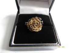 A LADY`S 9ct HALLMARKED GOLD RING, SIZE J IN THE FORM OF A ROSE SET WITH THREE BLUE STONES TO THE