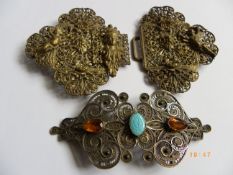 TWO ORNATE NURSE`S BUCKLES, ONE DEPICTING ROSES AND CHERUBS THE OTHER SILVER METAL FILIGREE SET WITH