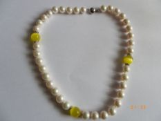 A STRING OF FRESHWATER CULTURED PEARL NECKLACE, SET WITH YELLOW CAT EYE STONE - 10 / 11mm