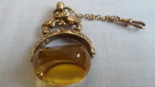 A VICTORIAN YELLOW CUT GLASS FOB IN ELABORATE GOLD PLATED MOUNT ON GOLD SAFETY CHAIN, APPROX. FOB