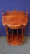 A REPRODUCTION INTRICATELY CARVED CANTERBURY WITH TURNED SUPPORTS AND SHELF WITH FOUR MAGAZINE
