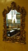 AN ORNATE ROCOCO STYLE GILT EFFECT HALL MIRROR, APPROX. 77 x 48 cms.