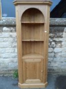 A Pine Corner Cabinet. The cabinet having an arched top with cornice, two shaped shelves below and a