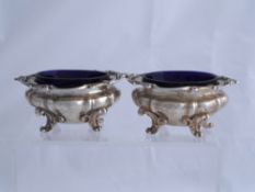 Two solid silver William IV Salts.  The salts on scroll feet benefit from the original blue glass