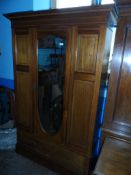 An Edwardian Wardrobe. The inlaid mahogany wardrobe having a single bevelled glass mirrored door