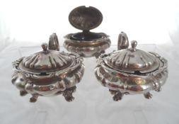 A set of three solid silver Mustard Pots. The lidded melon shaped mustards on scroll feet benefiting