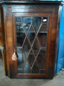 An Antique Mahogany Corner Cabinet. The cabinet having a glazed door to the front and two shaped