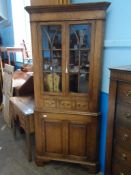 A Bespoke Oak Corner Cabinet. The cabinet having glazed doors and three drawers to the top with a