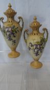 A PAIR OF ROYAL VIENNA TURE PORCELAIN LIDDED URNS, HAND PAINTED WITH WISTERIA, THE TWO HANDLED