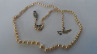 A STRING OF VINTAGE GRADUATED NATURAL PEARLS ON AN 18 K CLASP M.M M B, THE DECO STYLE CLASP SET WITH
