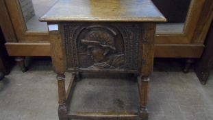 AN ANTIQUE OAK FIRESIDE BOX HAVING A CARVED HEAD OF A ROMAN SOLDIER TO THE FRONT, THE INTERIOR BEING