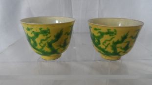 A PAIR OF CHINESE YELLOW AND GREEN TEA BOWLS DEPICTING CHASING DRAGONS AMONGST CLOUD SCROLLS AND