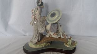 A LLADRO PORCELAIN STUDY OF `GEISHA ON A FOOTBRIDGE` WITH HERON AT THEIR FEET, ON WOODEN PLINTH,