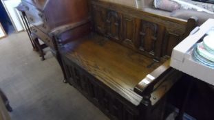 AN OLD CHARM OAK SETTLE HAVING DECORATED PANELLING TO THE FRONT, WITH PANELLED BACK AND SIDES,