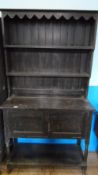 AN EDWARDIAN DARK OAK COTTAGE DRESSER HAVING TWO OPEN SHELVES TO THE TOP WITH SCALLOPED DECORATION