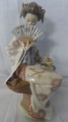 A LLADRO PORCELAIN FIGURINE OF A `DEMURE SEATED GEISHA ` 24 cms.