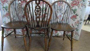 A SET OF SIX WHEEL BACK DINING CHAIRS ON TURNED LEGS AND STRETCHERS.