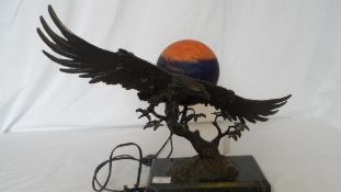 A BRONZE CAST LAMP BASE DEPICTING AN EAGLE ON A GREEN MARBLE BASE. THE LAMP BASE HAVING A GLOBE OF