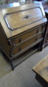 AN EDWARDIAN OAK DROP FRONT BUREAU HAVING TWO DRAWERS BELOW ON BARLEY TWIST LEGS WITH STRETCHERS,