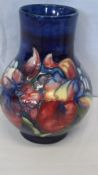 AN A W. MOORCROFT VASE - IRIS AND SPRING FLOWER DESIGN ON BLUE GROUND, 17.5 cms HEIGHT. SIGNED IN