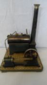 A VINTAGE MODEL STATIONARY TIN REPLICA OF A TRACTION STEAM BOILER ON A WOODEN PLINTH.