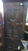 AN ANTIQUE OAK TRIANGULAR CORNER CUPBOARD - TWO PANELLED DOORS ON SHAPED LEGS - BEADED FRIEZE TO