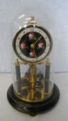 A KONRAD MAUCH DOMED TORSION BRASS CLOCK ON METAL BASE. 21 cms.