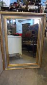 AN ORNATE GILT FRAMED WALL MIRROR HAVING BEVELLED GLASS, APPROX. 113 X 82 cms