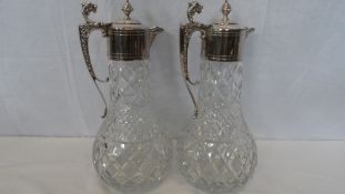 A PAIR OF EDWARDIAN SILVER PLATED CUT GLASS CLARET JUGS HAVING ACORN FINIALS AND LION HEAD THUMB