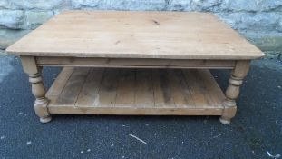 AN ANTIQUE PLANKED PINE COFFEE TABLE ON TURNED LEGS AND HAVING AN UNDER SHELF, APPROX. 122 X 90 X 45