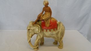 A PLASTER FIGURE OF AN INDIAN BOY ON AN ELEPHANT HAVING IMPRESSED INSIGNIA LC TO BASE AND 193.